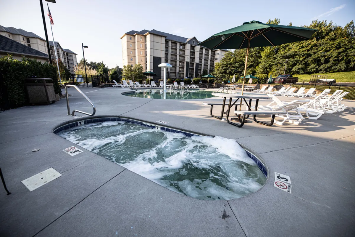 This image features the resort’s inviting outdoor swimming pool area, complete with a hot tub, ample lounge chairs, and umbrellas for shade. The atmosphere is leisurely and social, ideal for family relaxation and group gatherings.
