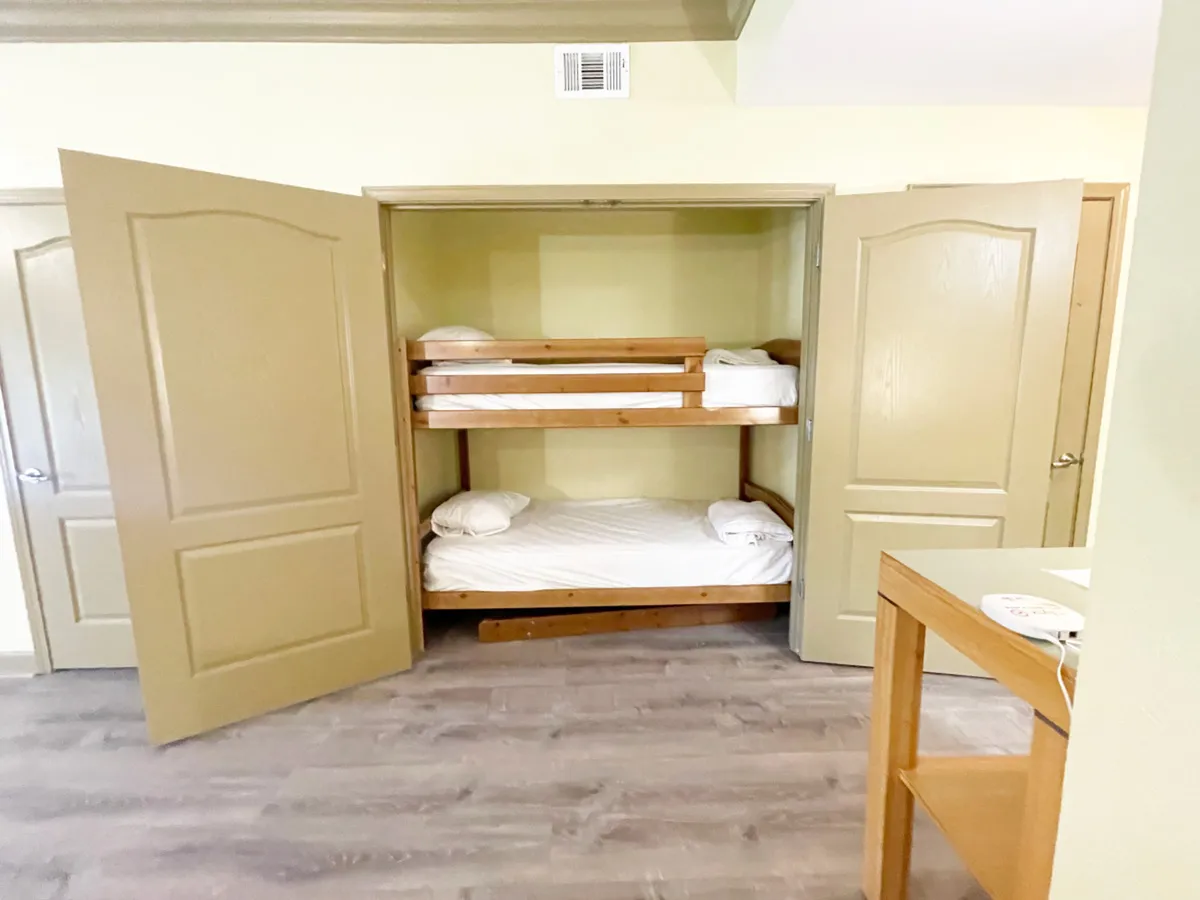 A playful, cozy interior featuring bunk beds with open closet doors and wooden furniture. The space feels relaxed and fun, ideal for late-night chats, storytelling, or unwinding after a day out.